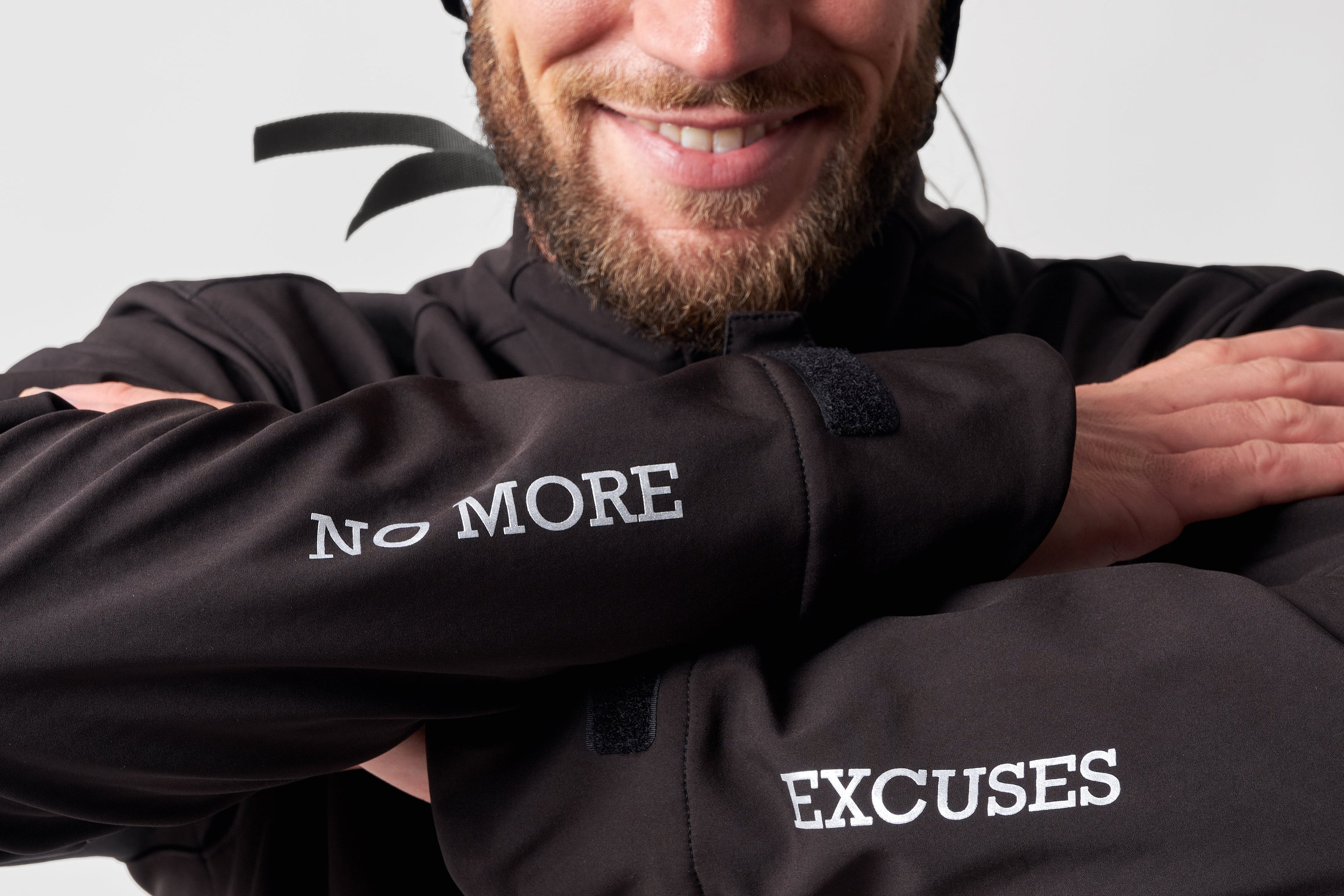 Person wearing a black jacket with motivational text and a helmet on a light gray background